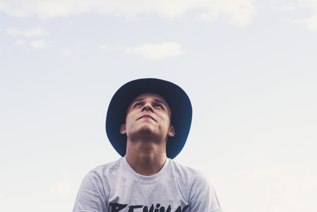 Teenager with hat looking up to sky