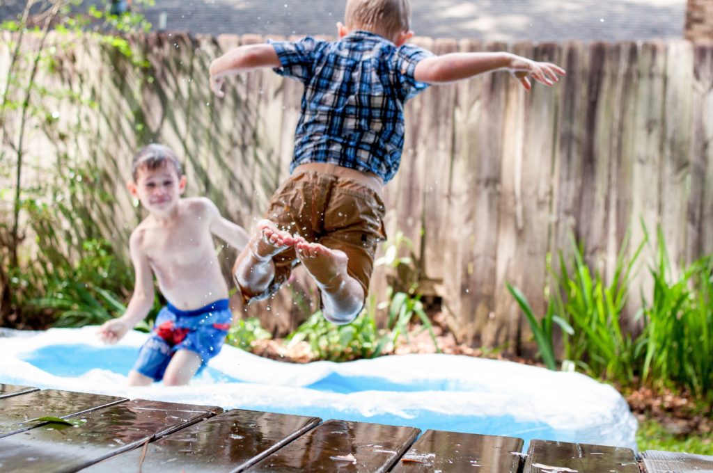 Two young boys in playing in a small kiddie pool in the backtard